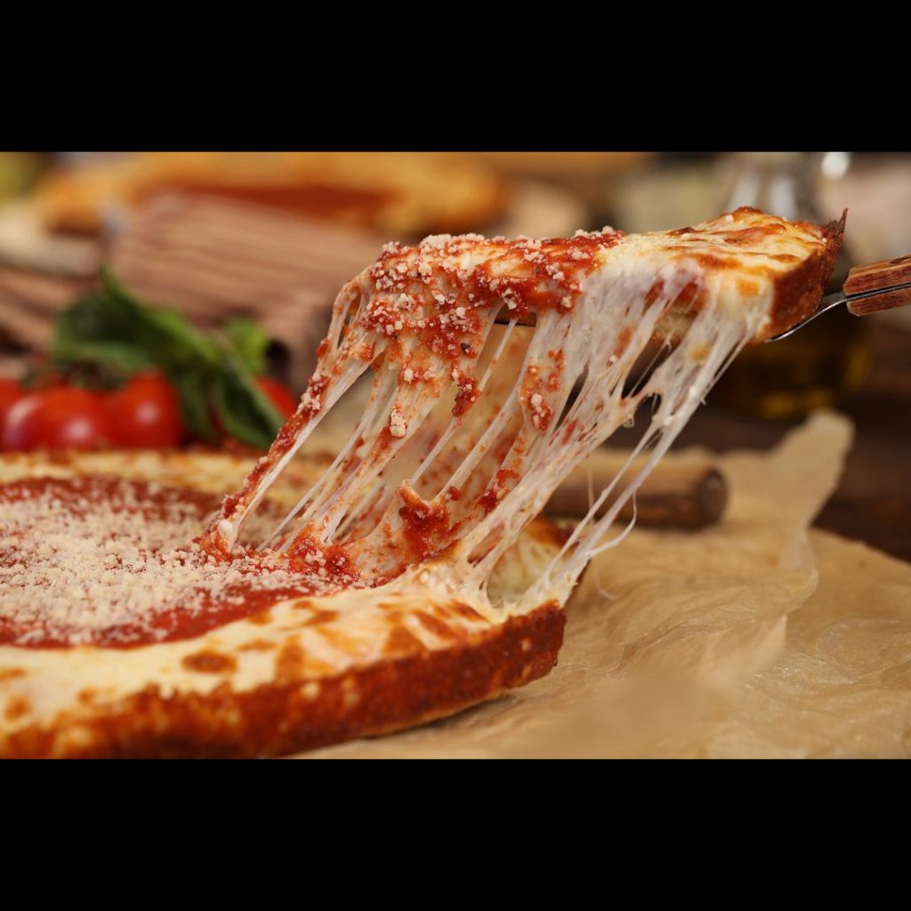 Close up a cheese pull as a slice of pizza is lifted away from the rest of the pizza