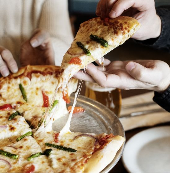 Patrons grabbing a slice of pizza with Bacio cheese